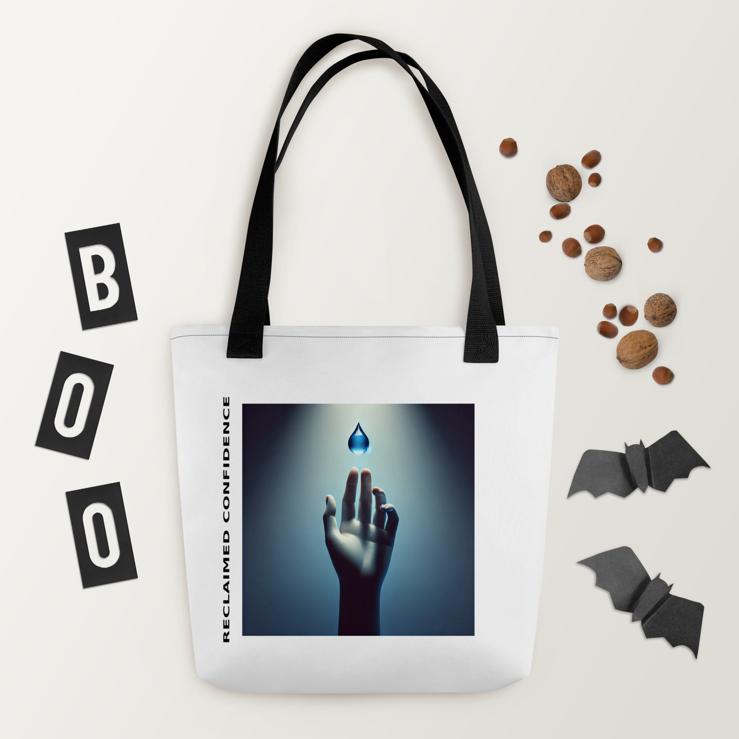 White tote with black handles featuring surreal graphic of a hand reaching toward a glowing object. Surrounded by fall-themed decor.